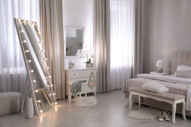 Yatak odasında ampulleri ve çekmeceleri olan büyük bir ayna. İç tasarım