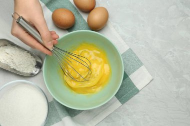 Gri masada yumurta çırpan bir kadın, üst manzara. Metin için boşluk