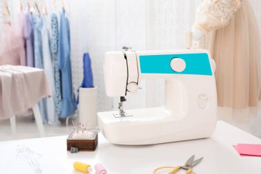 Modern dikiş makinesi ve aksesuarlar terzilik atölyesinde masanın üzerinde.