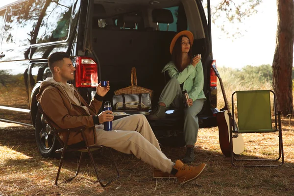 Çift Arabanın Yanında Dinleniyor Kamp Alanında Sıcak Içkinin Tadını Çıkarıyor — Stok fotoğraf