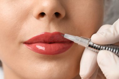 Kuaförde kalıcı olarak dudak makyajı yapılan genç bir kadın.