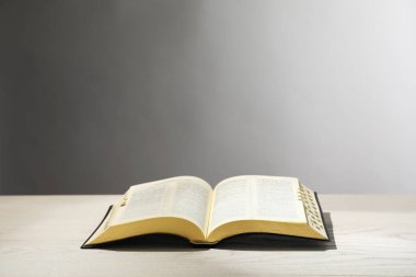 Açık gri arka plana karşı beyaz ahşap masada İncil 'i açın. Hıristiyan dini kitabı