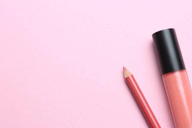 Pembe arka planda parlak dudak kalemi ve sıvı ruj, metin için yeri olan düz bir yer. Kozmetik ürünleri