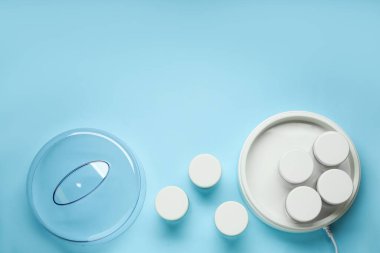 Açık mavi arka planda kavanozları olan modern yoğurt imalatçısı. Metin için boşluk