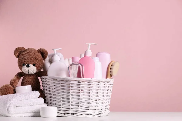 위에서 분홍색 배경에 대비하여 바구니 액세서리 장난감 곰등에 아기용 화장품이다 — 스톡 사진