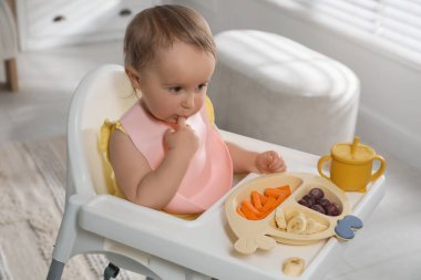 Evde yemek yerken önlük takan şirin bir bebek.