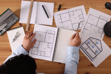 Ahşap masada çizim defteri ve kalemi olan bir adam.