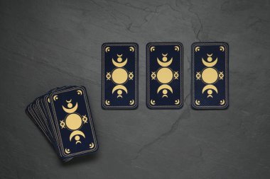 Tarot kartları siyah masada, düz yerde. Ters taraf