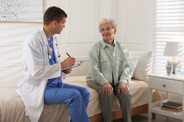 Bakıcı odada yaşlı bir kadını muayene ediyor. Ev sağlık hizmetleri