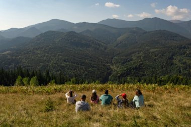 Bir grup turist dağlarda, arka planda oturuyor.