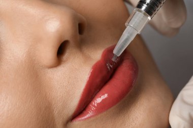 Kuaförde kalıcı olarak dudak makyajı yapılan genç bir kadın.