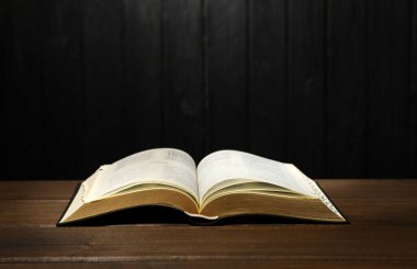 Masadaki İncil 'i siyah ahşap arka plana karşı aç. Hıristiyan dini kitabı