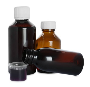 Öksürük şurubu şişeleri ve beyaz arka planda ölçü kabı