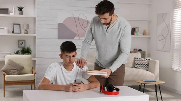 Αυστηρός Πατέρας Βιβλία Μαλώνουν Τον Γιο Του Ενώ Χρησιμοποιεί Smartphone — Φωτογραφία Αρχείου