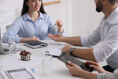 Emlakçı ofisteki genç çifte ev anahtarını veriyor, yakın plan. İpotek kavramı