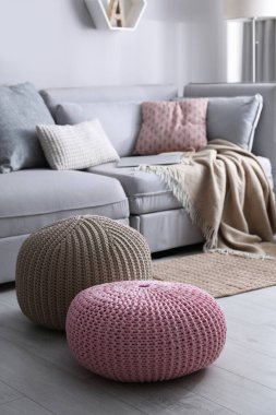 Oturma odasındaki kanepenin yanında süslü püslü puflar. İç öge