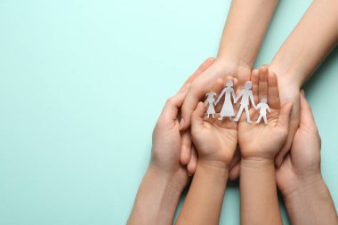Ebeveynler ve çocukları açık mavi arka planda kağıt kesiği tutuyorlar. Metin için boşluk
