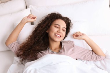 Mutlu Afrikalı Amerikalı kadın yatakta uyandı.
