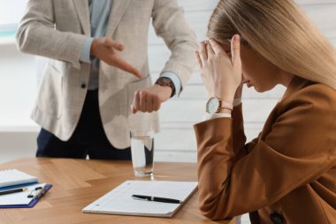 İş adamı, çalışanı ofise geç kaldığı için azarlarken kol nöbetini işaret ediyor.
