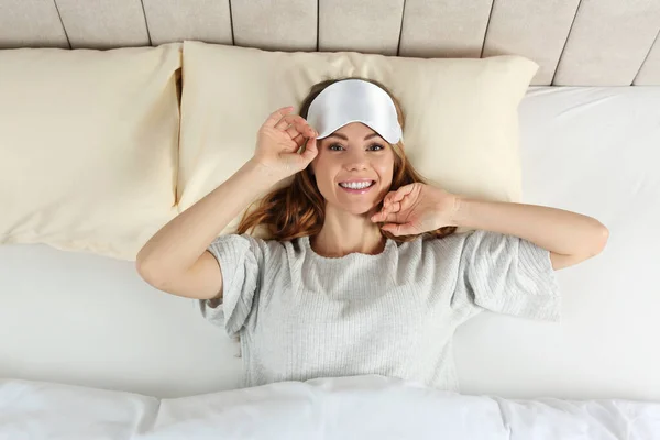 ベッドの中で睡眠マスクを持つ美しい女性 トップビュー — ストック写真