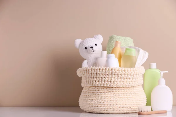 用婴儿化妆品 浴具和玩具熊编织的篮子 在米色背景下放在白桌上 案文的篇幅 — 图库照片