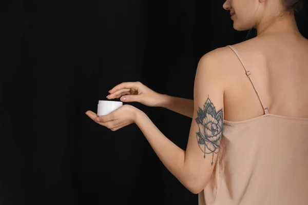 Mulher Com Tatuagem Segurando Frasco Creme Contra Fundo Escuro Close — Fotografia de Stock