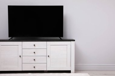 Beyaz duvarın yanındaki dolapta modern televizyon var. Metin için boşluk