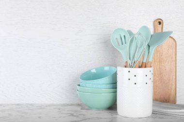 Mutfak gereçleri, seramik tabaklar ve beyaz mermer masa üzerinde tahta kesme tutacağı. Metin için boşluk