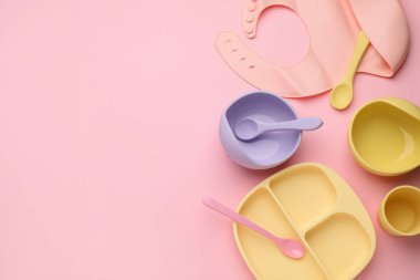 Pembe zemin üzerinde bebek beslenme aksesuarları ve önlüğü ile düz kompozisyon, metin için boşluk