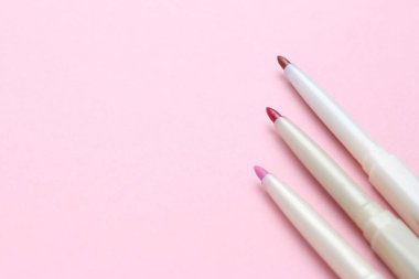 Pembe arka planda dudak kalemi, metin için boşluk. Kozmetik ürünü