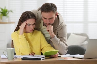 Genç çift oturma odasında aile bütçesini tartışıyor.