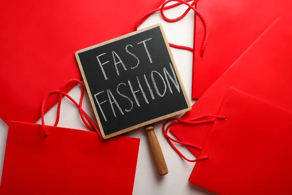 白い背景に高速ファッションと赤のショッピングバッグ トップビューと小さな黒板 — ストック写真