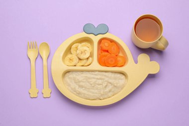 Tabakta sağlıklı bebek mamaları ve menekşe arka planda içkili bardaklar, düz uzanmış.
