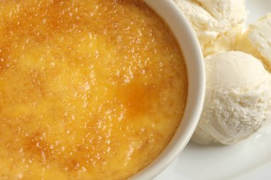 Lezzetli creme brulee ve tabakta bir kepçe dondurma, yakın plan.