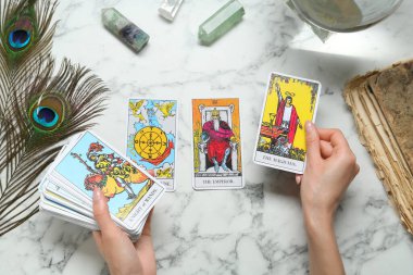 Beyaz mermer masadaki tarot kartlı kadın, üst manzara.