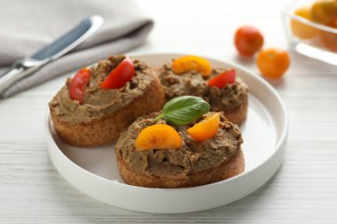 Lezzetli ezmeli taze ekmek dilimleri ve beyaz ahşap masadaki domatesler, yakın plan.