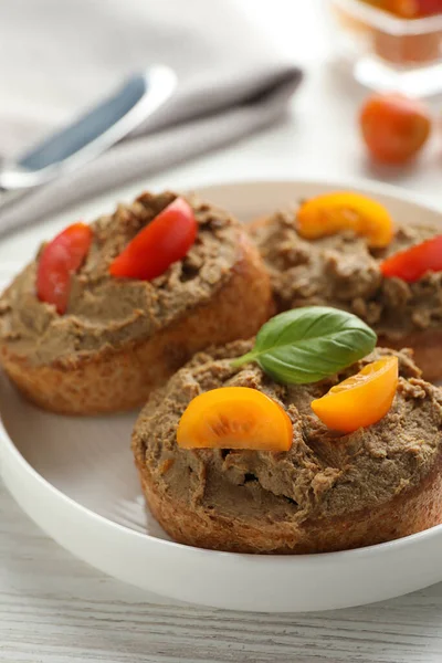 Lezzetli ezmeli taze ekmek dilimleri ve beyaz ahşap masadaki domatesler, yakın plan.