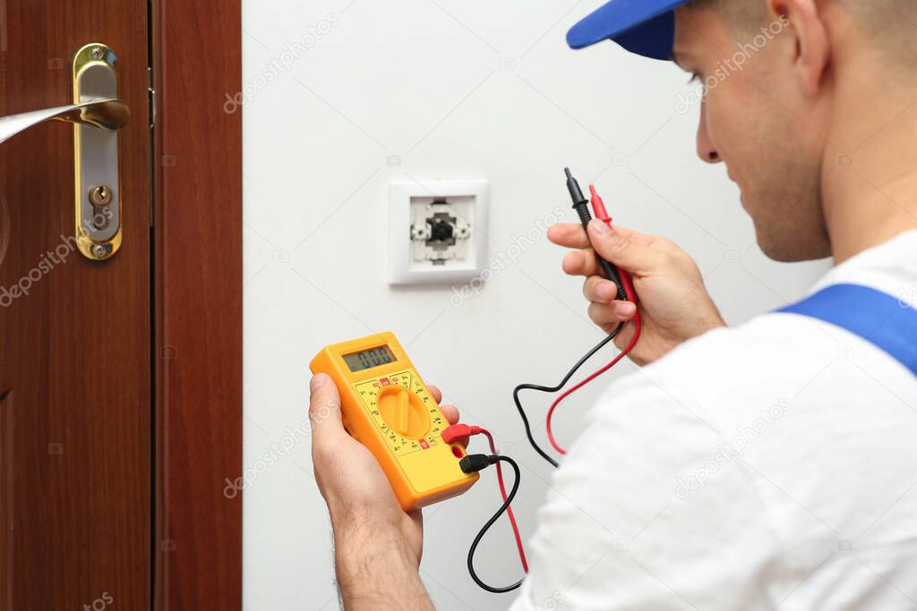 Professional electrician with voltage tester near power light switch indoors, closeup