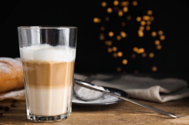 Lezzetli latte macchiato, kruvasan ve kahve çekirdekleri ahşap masada. Metin için boşluk