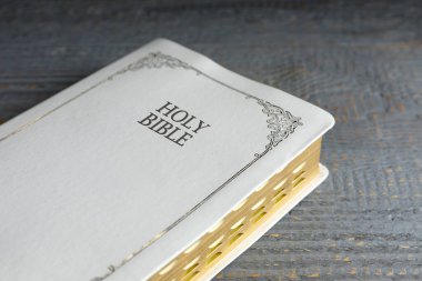 Gri ahşap masada eski bir İncil, yakın plan. Dini kitap