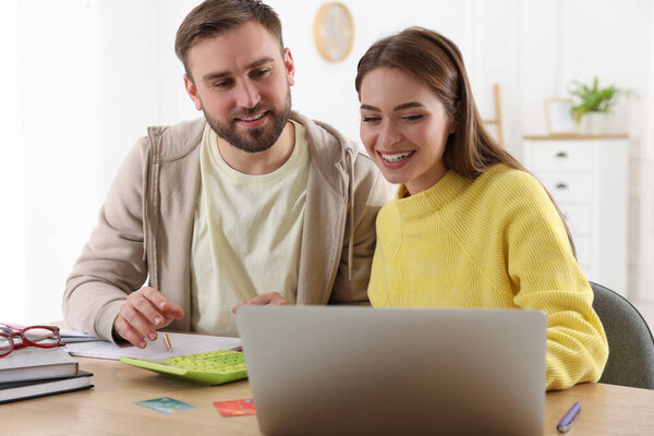 Young couple discussing family budget at table in living room