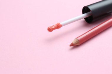 Dudak kalemi ve pembe arka planda sıvı ruj fırçası, mesaj için boşluk. Kozmetik ürünleri