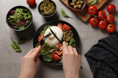 Gri masada nefis burrata salatası yiyen bir kadın.