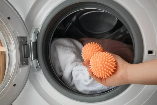 洗濯機にドライヤーボールを入れる女 — ストック写真