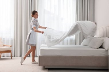Otel odasında yatak yapan profesyonel oda hizmetçisi.