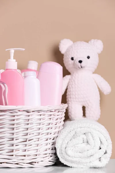 配有婴儿化妆品 浴具和针织玩具熊的柳条筐 以米色为背景放在白桌上 — 图库照片
