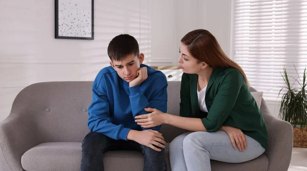 Mother consoling her depressed son at home. Teenager problems