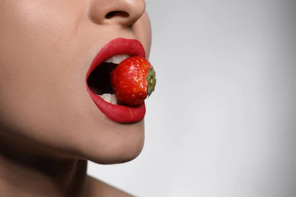 Młoda Kobieta Pięknymi Ustami Makijaż Jedzenie Truskawki Jasnym Tle Zbliżenie — Zdjęcie stockowe