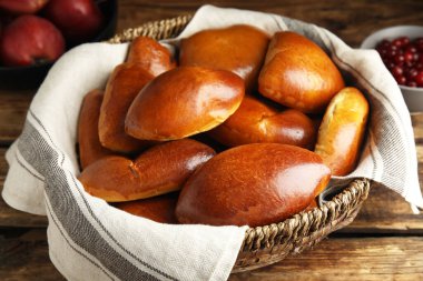 Hasır sepetin içinde ahşap masanın üzerinde nefis pirozhki.
