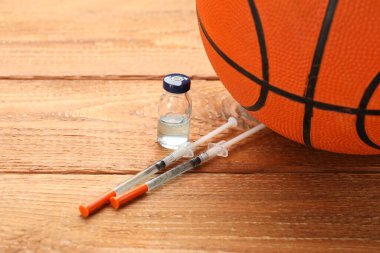 Basketbol topu, şırıngalar ve şişe ahşap masada, yakın plan. Doping kavramı